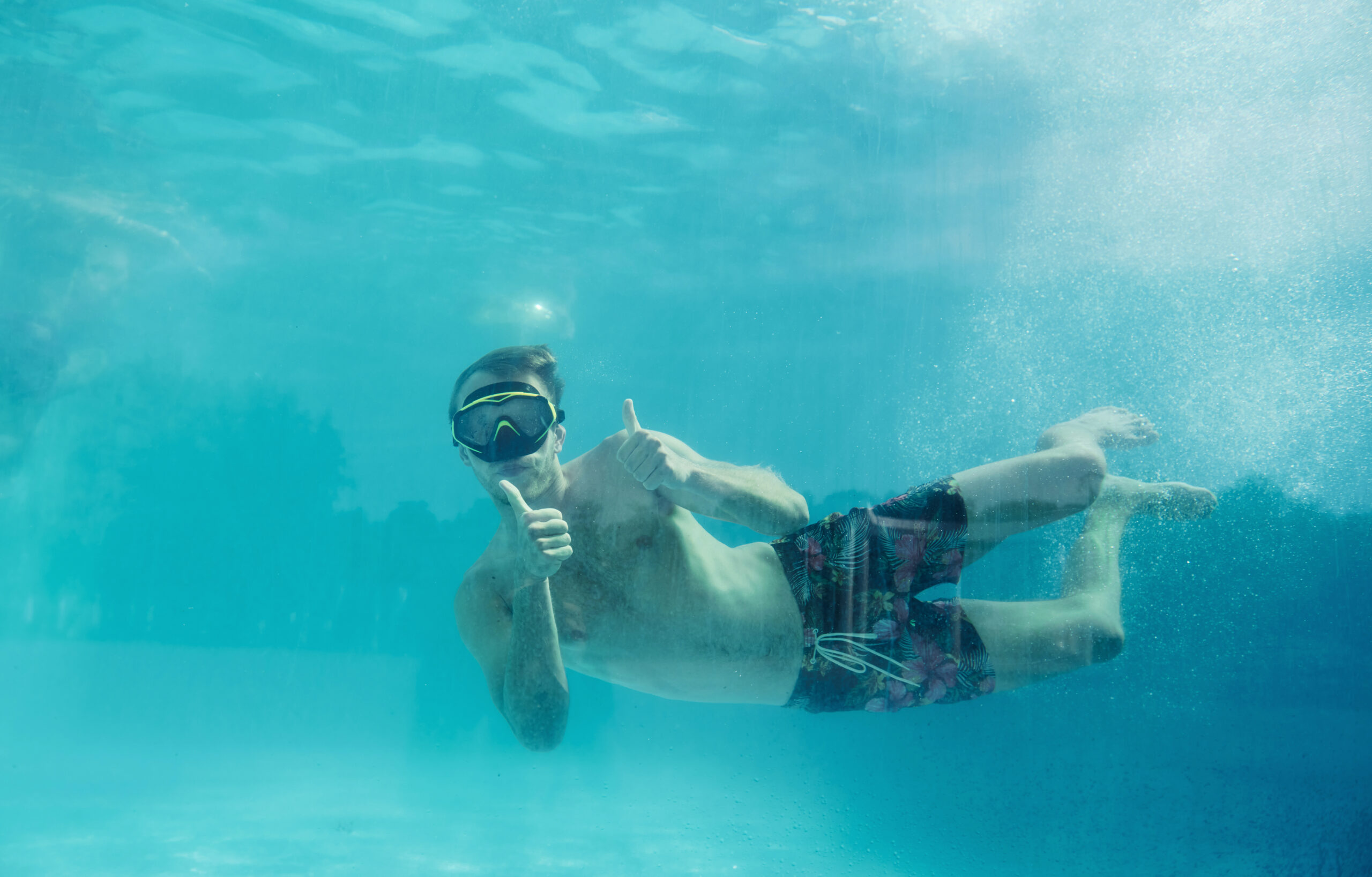 Man swimming underwater in the pool at daytime. Having fun.