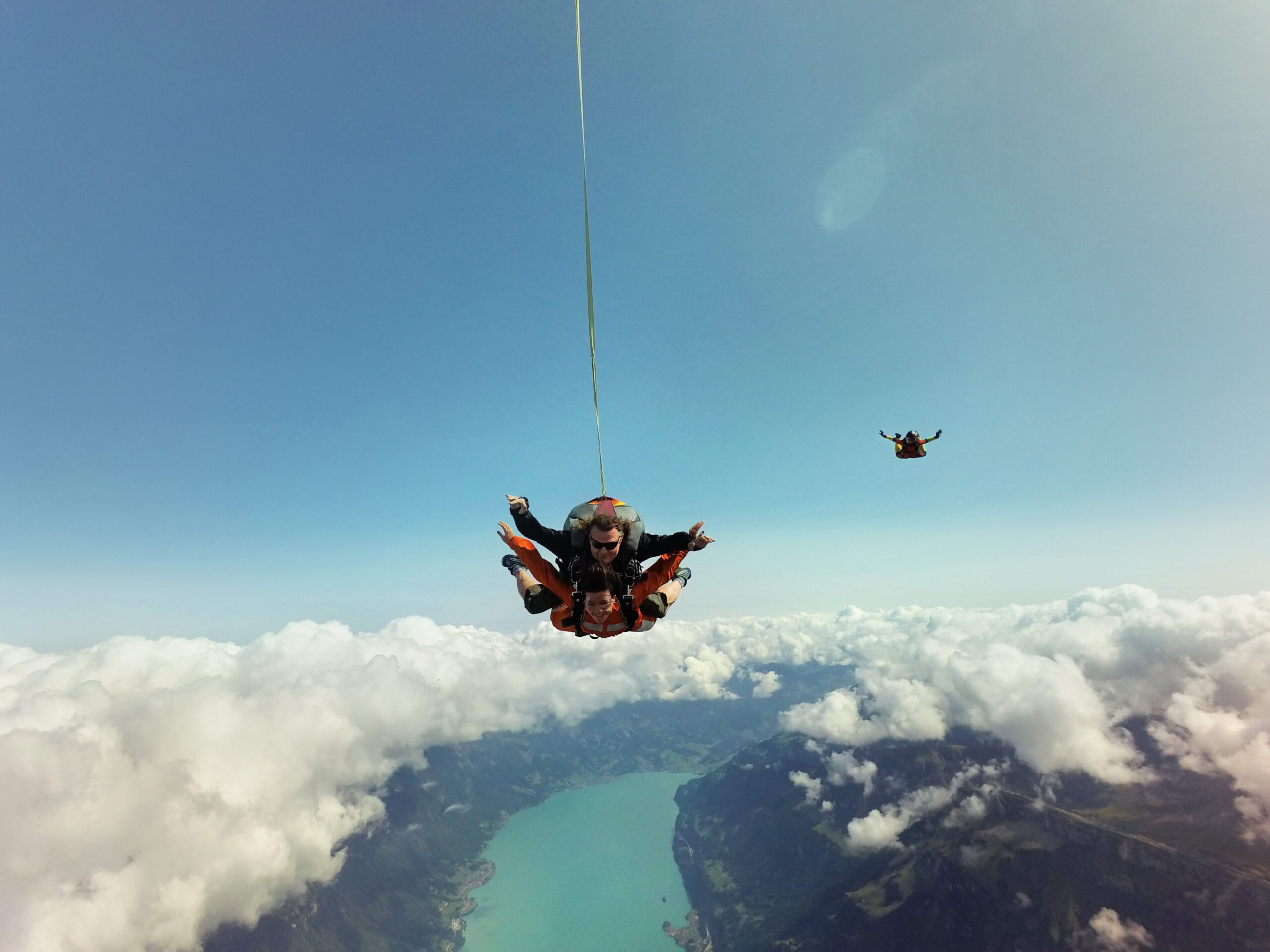 Portrait of tandem skydivers above clouds and landscape