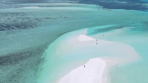 Visitors walking in the crystal-clear shallow lagoon of Île aux Cerfs during a day tour in Mauritius