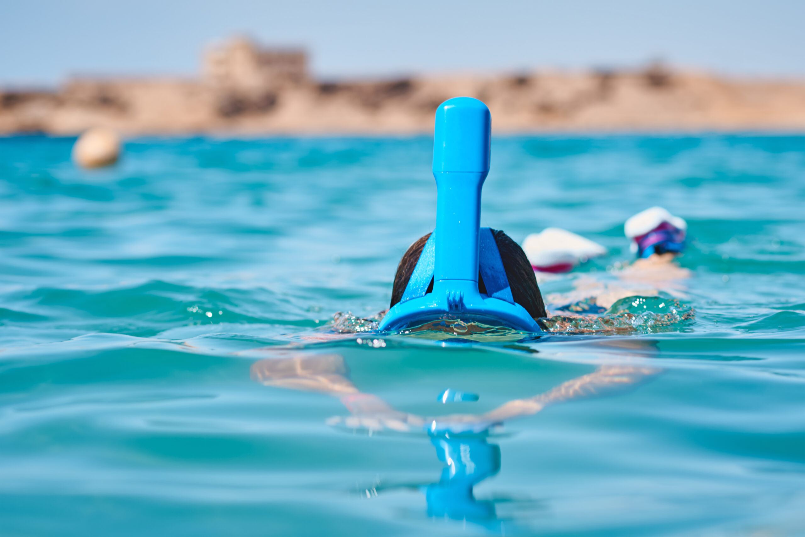 Woman with snorkel full face mask diving in blue sea. Summer vacation