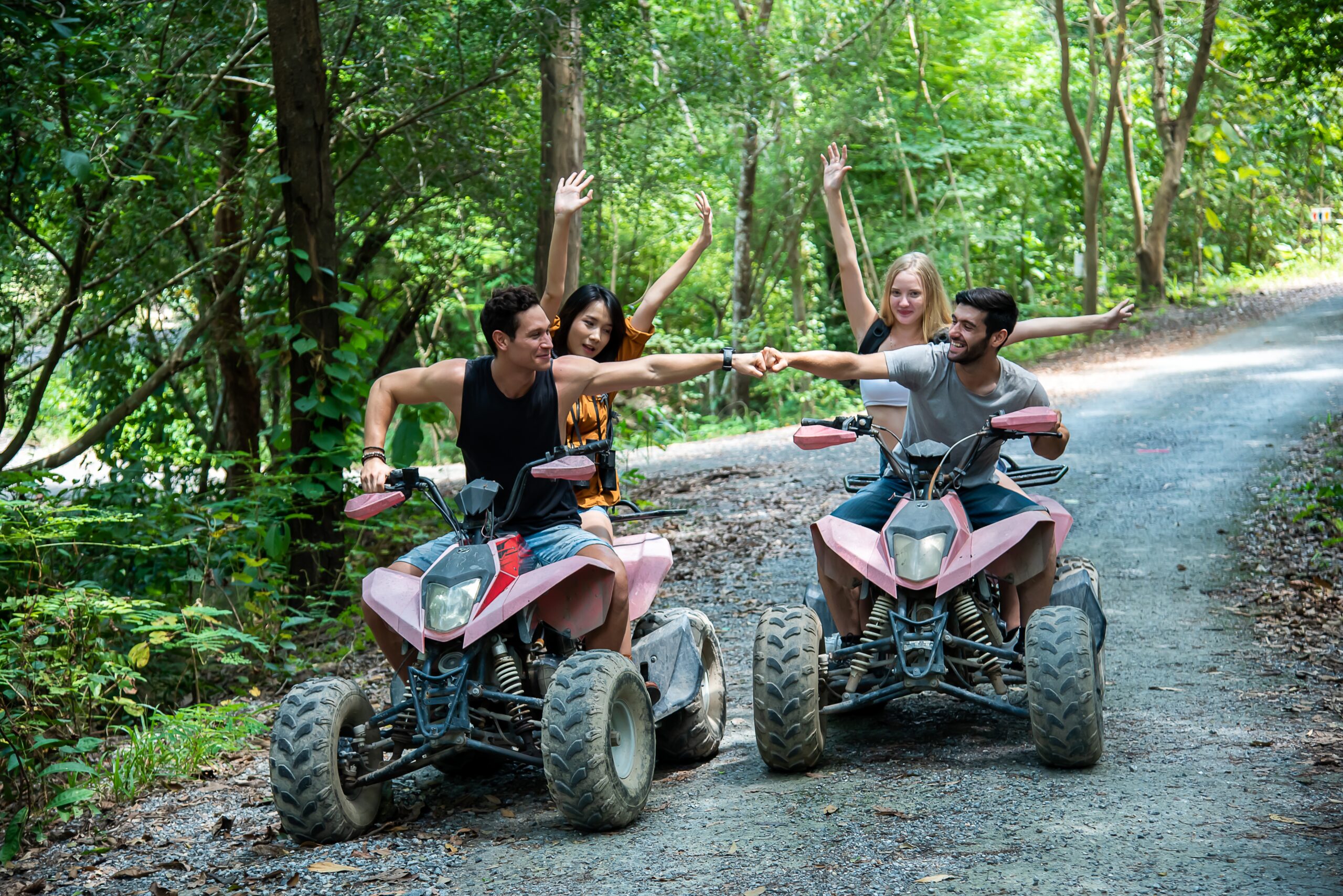 young couple or friend happily touches their hands while riding an ATV in the forest.
