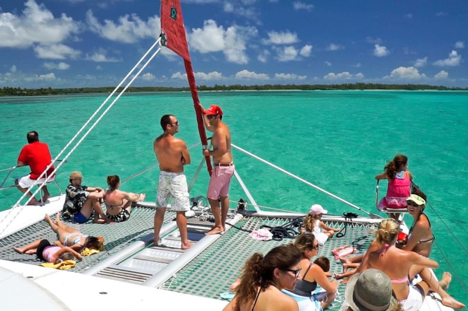 Group relaxing and taking photos on deck of catamaran during Île aux Cerfs cruise