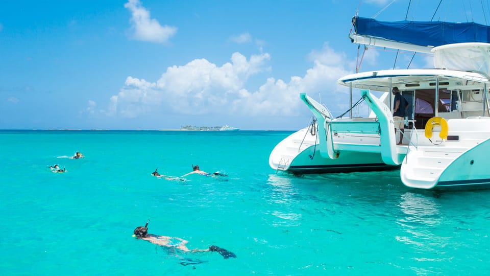 Snorkelers enjoying clear blue waters near Île aux Cerfs with catamaran in the background