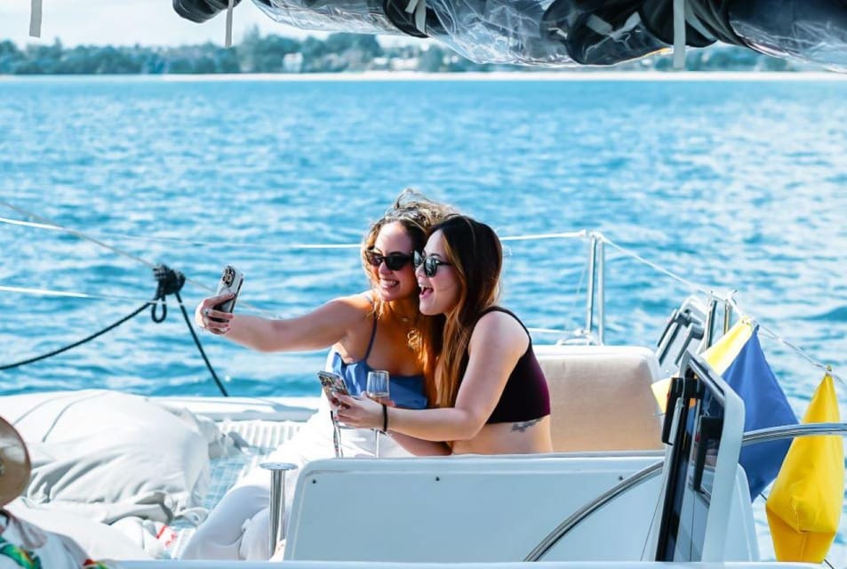 Two women taking a selfie on a catamaran surrounded by turquoise waters near Flat Island