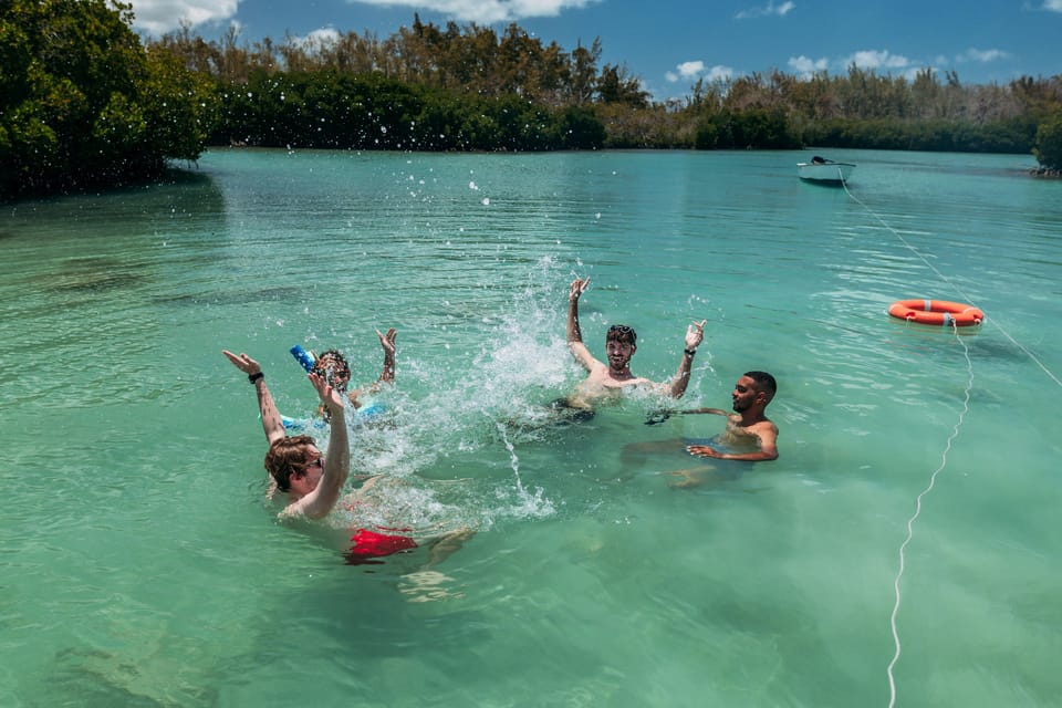 Group of people enjoying the crystal-clear water and playful splashing on Flat Island cruise