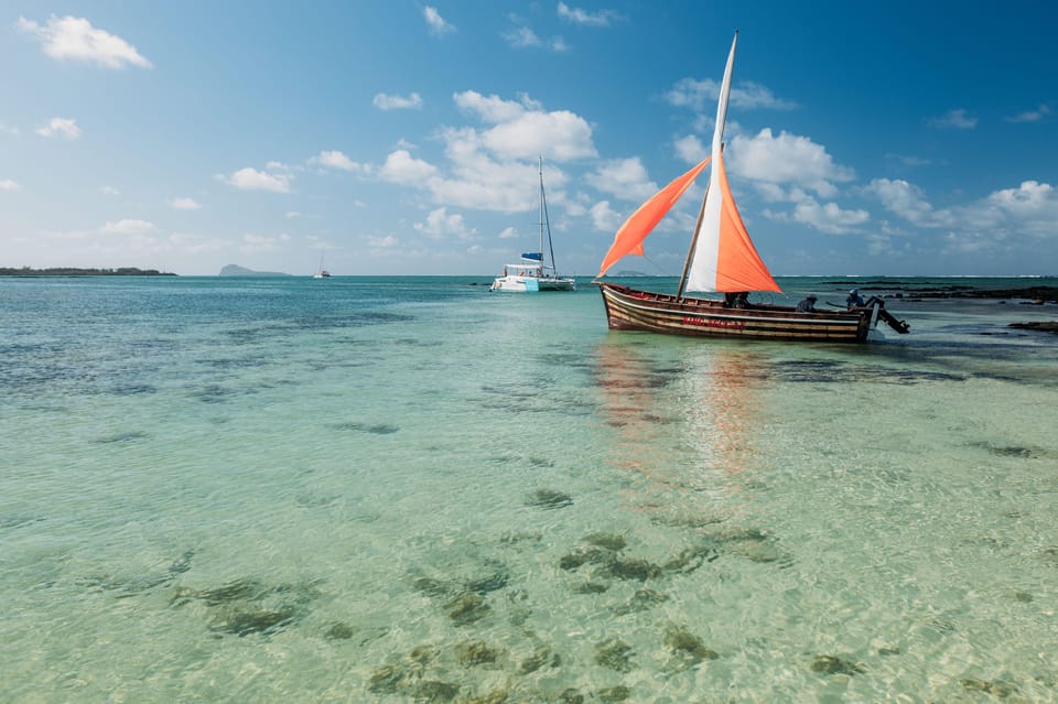 A wooden sailboat near the shallow beach of Flat Island with clear blue skies