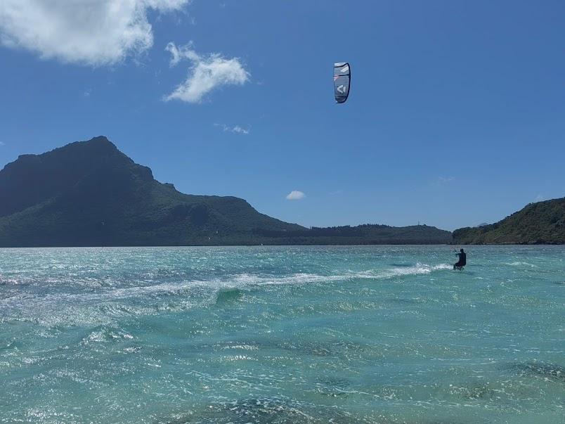 Kitesurfer riding waves at Le Morne with mountain backdrop