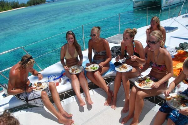 Tourists having lunch on a catamaran in clear blue waters of Gabriel Island, Mauritius