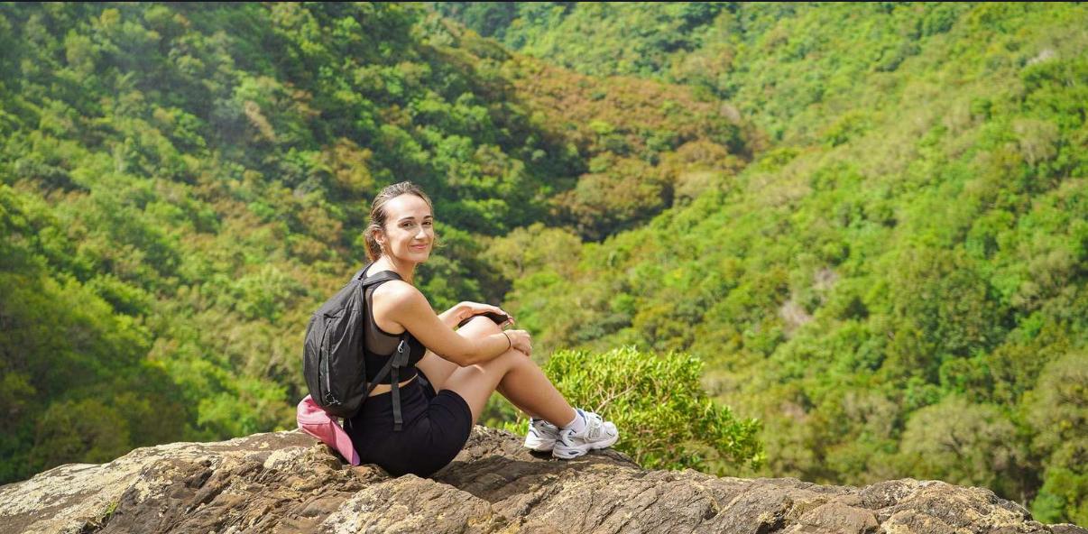 Female hiker resting on rock with scenic view of Tamarind Falls valley