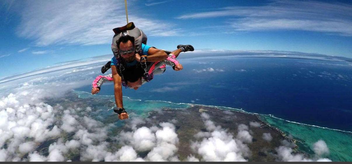 Tourist enjoying tandem skydive over the ocean and clouds in Mauritius